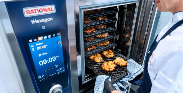 Chef removing grilled chicken from RATIONAL iHexagon combi oven using oven cloth.