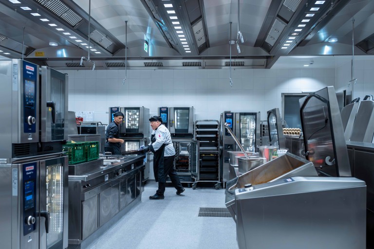 Professional kitchen with chefs using RATIONAL iCombi Pro combi-steamers and RATIONAL iVario Pro cooking systems.